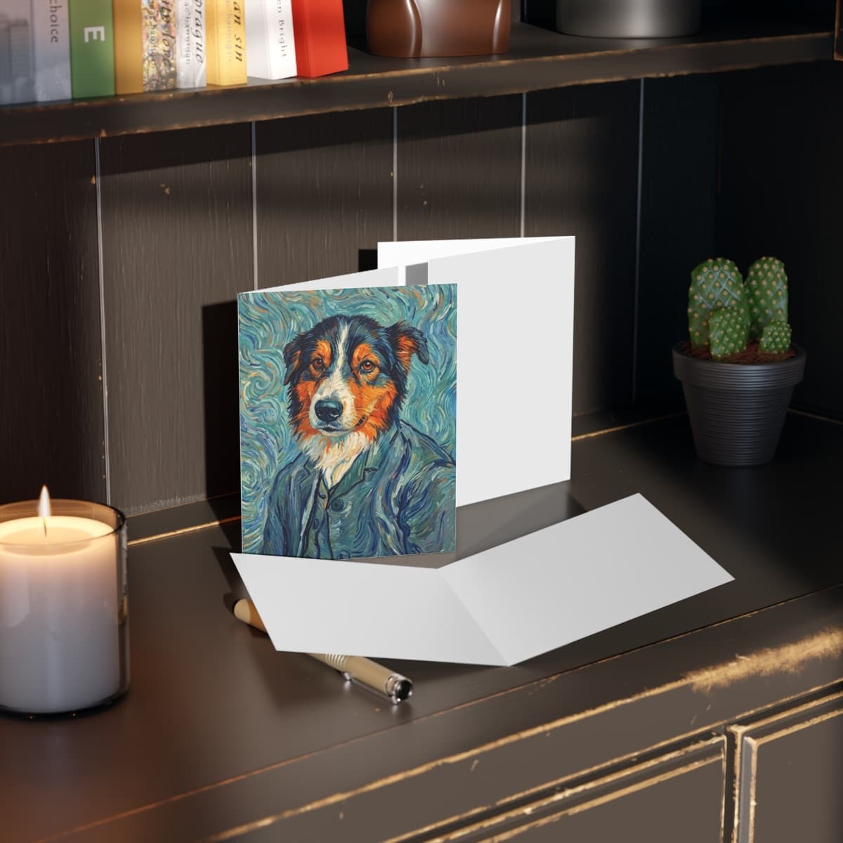 A folded greeting card printed with a swirling Van Gogh-style portrait of a border collie, standing open on a desk beside a lit candle.